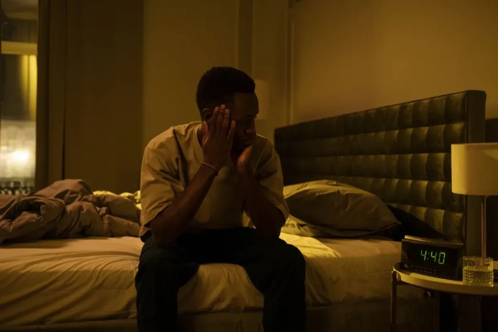 Signs Your Nervous System Is Dysregulated | The Reset Room 2 Man sitting on the edge of his bed in the early hours, clock showing 4:40